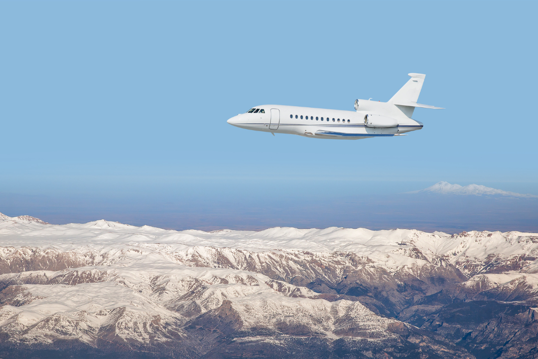 Private jet soaring over majestic snowy mountains, symbolizing luxury winter travel to exclusive ski destinations